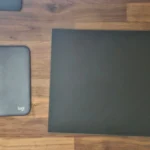 Bàn di chuột Logitech Studio series và một tấm lót chuột kính cường lực màu đen đặt cạnh nhau trên bàn
