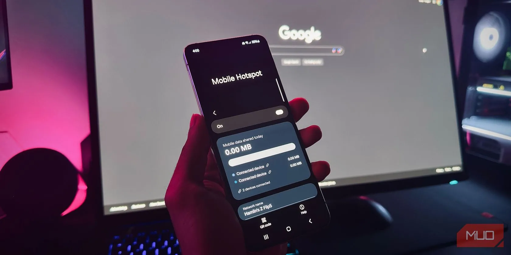 Bàn tay cầm điện thoại Android hiển thị tính năng Điểm phát sóng di động trước màn hình máy tính