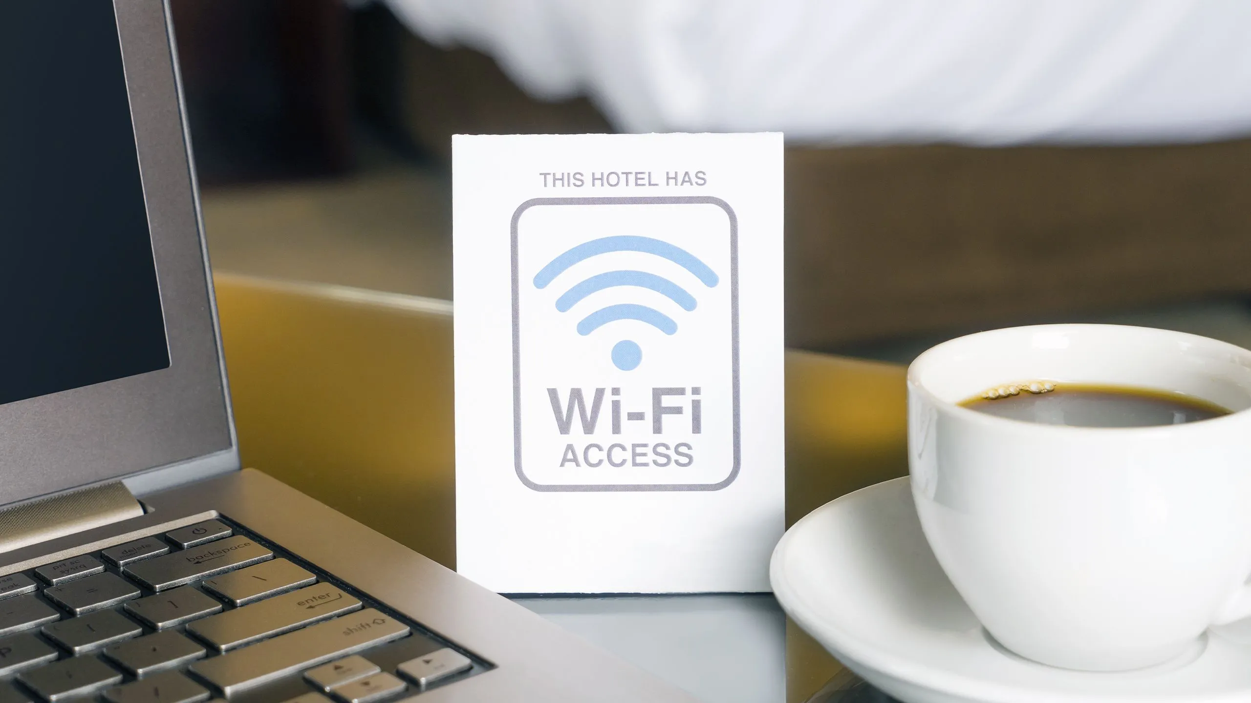 Biển báo Wi-Fi trong phòng khách sạn với laptop mở, tượng trưng cho việc kết nối internet chậm