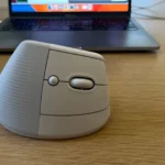 Chuột không dây Logitech Lift công thái học bên cạnh máy tính xách tay