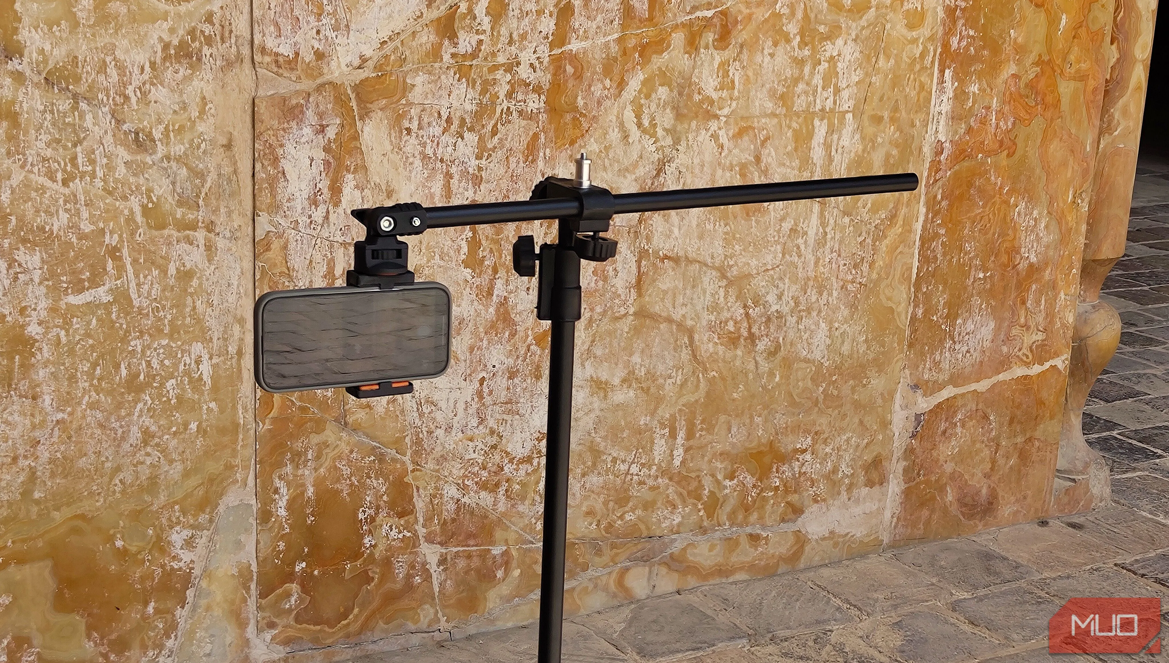 Điện thoại gắn trên tripod hướng về phía một bức tường cao, minh họa cách chọn chủ thể thẳng đứng để chụp panorama dọc.