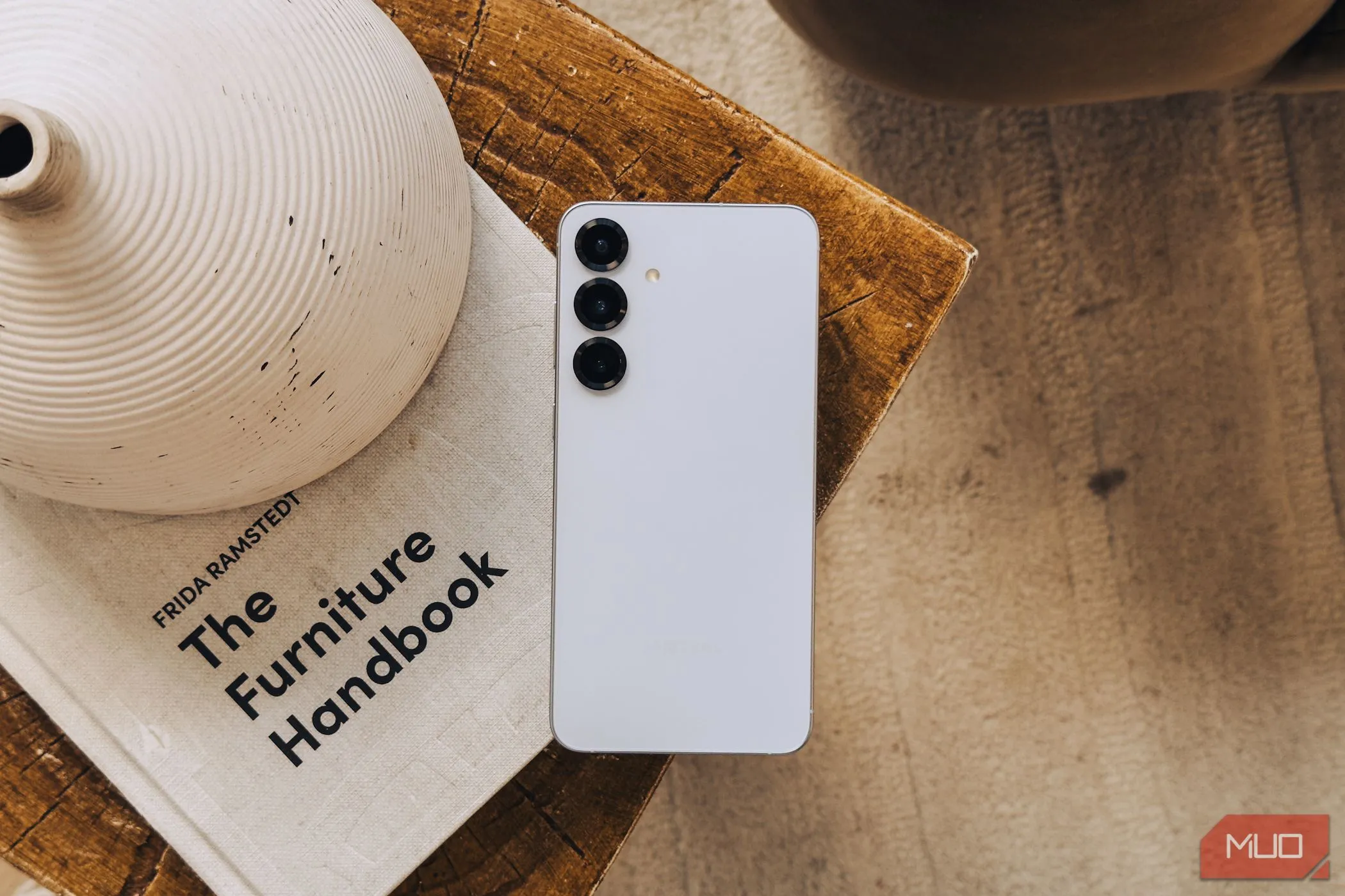 Điện thoại Samsung Galaxy S25 màu bạc đặt trên cuốn sách trắng, thể hiện cụm camera không có nâng cấp đáng kể.