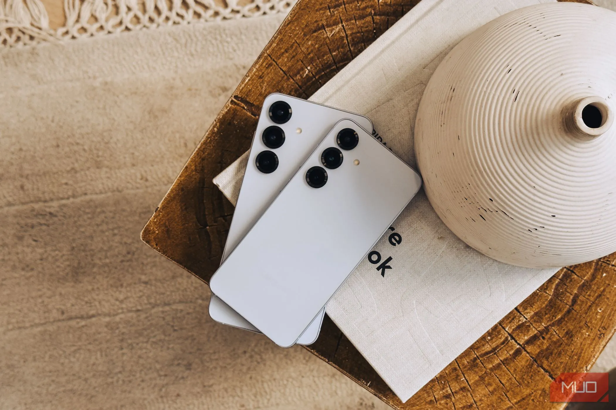 Điện thoại Samsung Galaxy S25 và S25+ đặt chồng lên nhau trên một cuốn sách