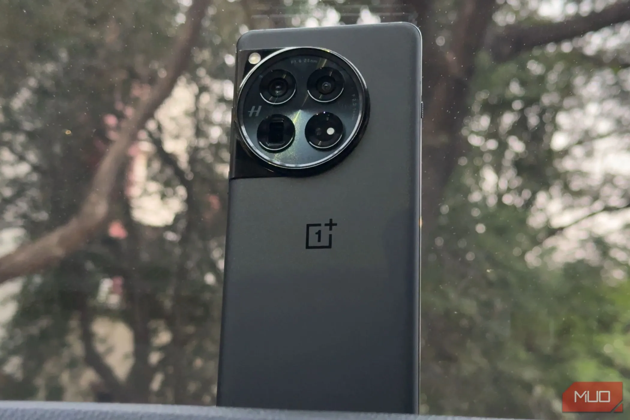 Hình ảnh chiếc điện thoại OnePlus 12 màu đen được đặt trên bảng điều khiển ô tô
