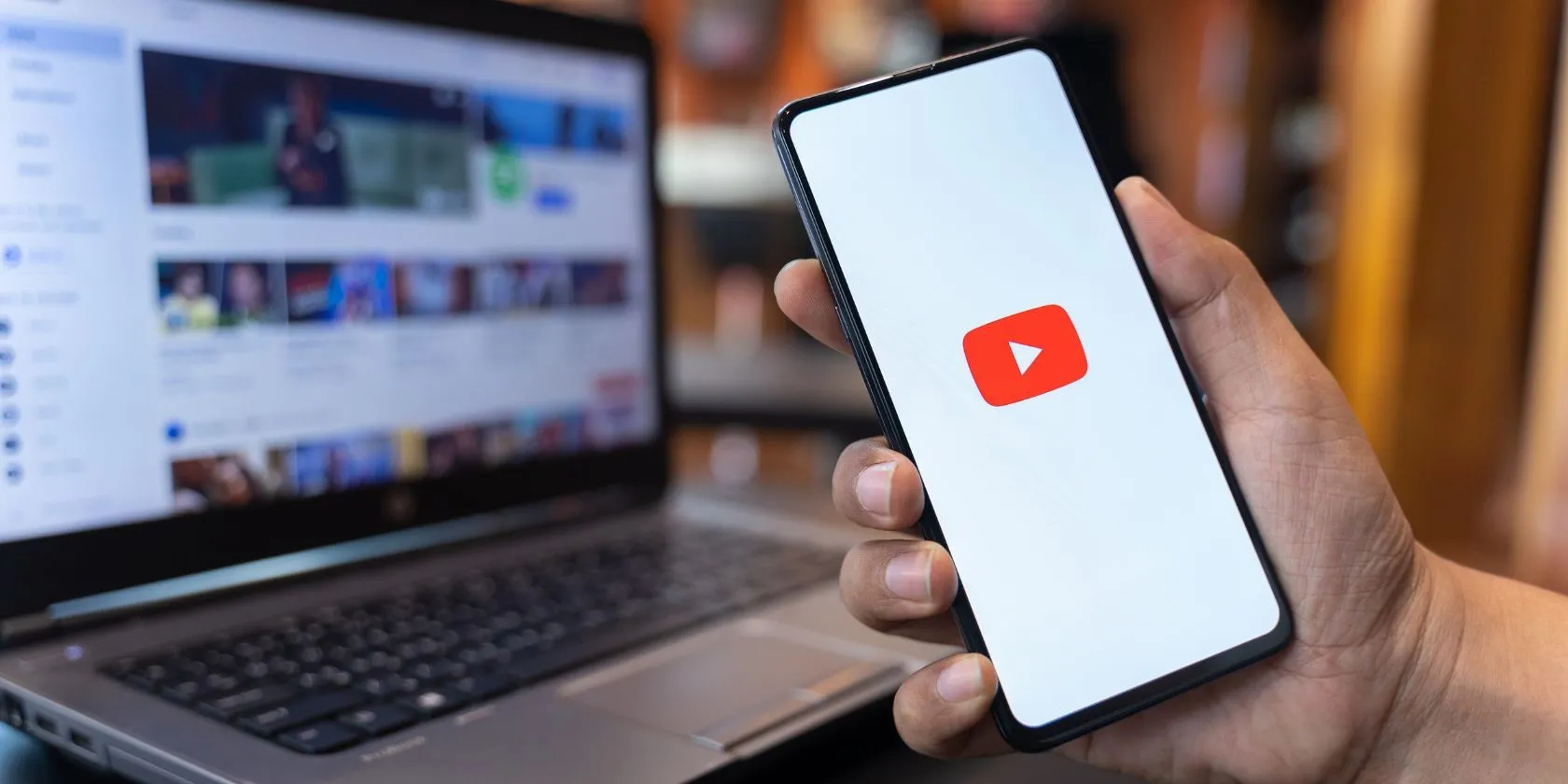 Hình ảnh một người đang dùng điện thoại với ứng dụng YouTube và website YouTube trên màn hình nền