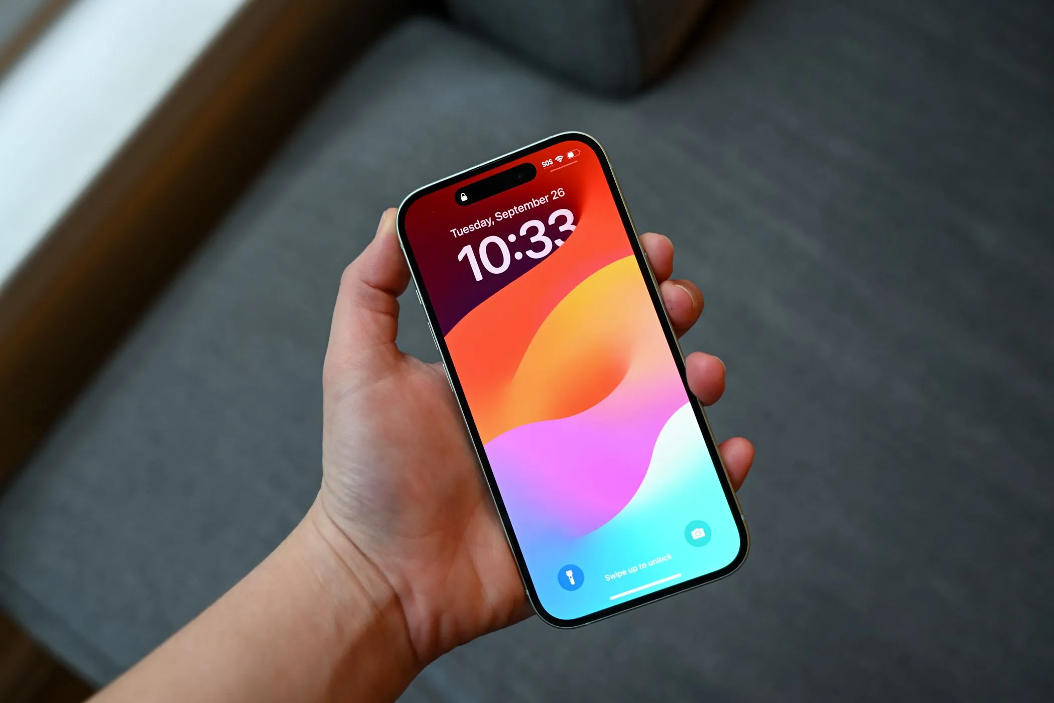 Hình ảnh người đang cầm iPhone 15 với màn hình khóa, minh họa cách dán chống nhìn trộm giúp che đi các vết xước nhỏ