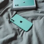 iPhone 11 màu xanh bạc hà đặt trên ga trải giường trắng tinh tươm