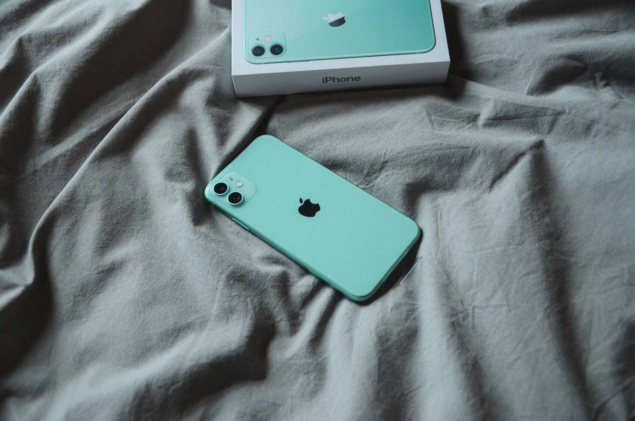 iPhone nằm trên chăn ga gối đệm khi đang sạc