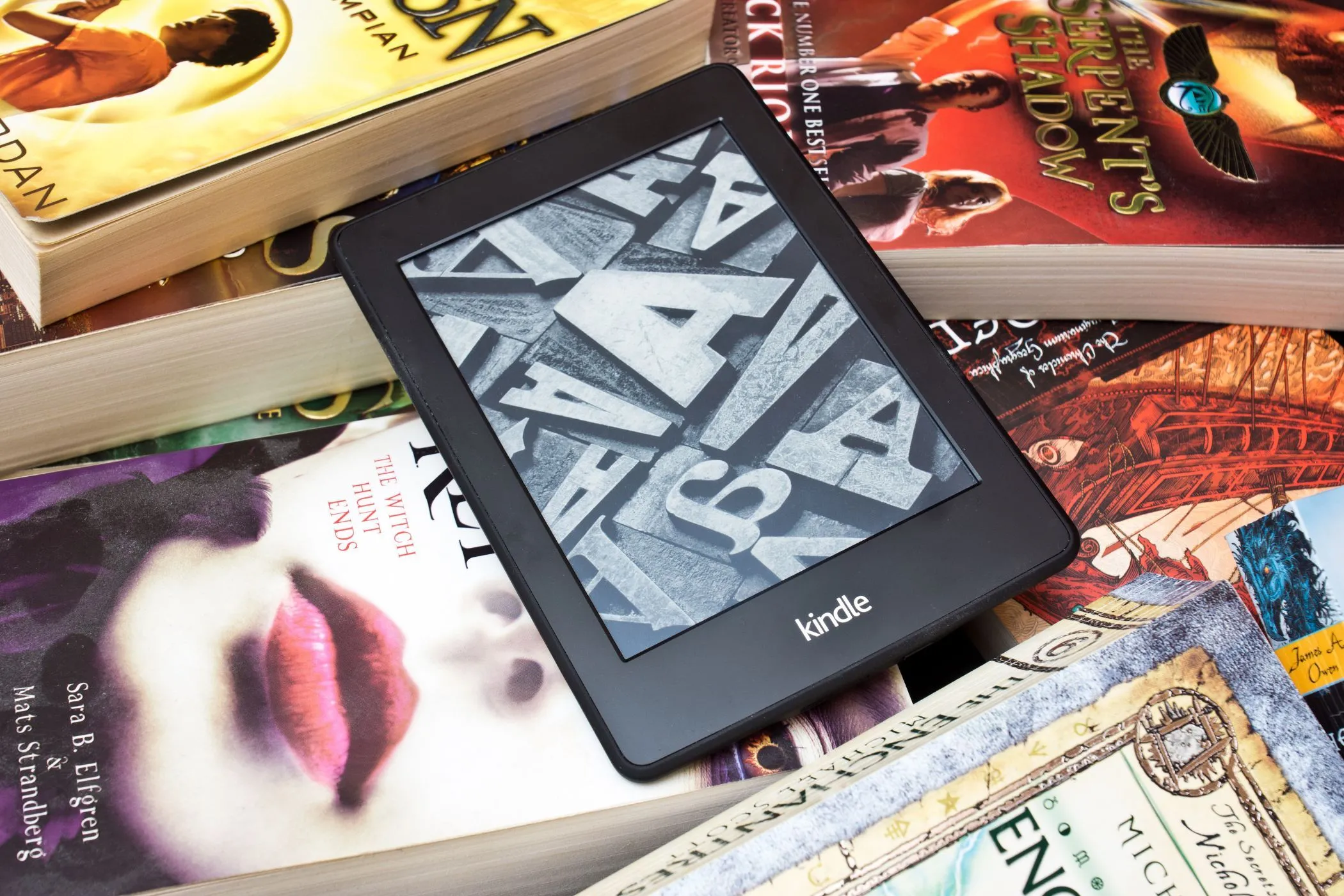 Kindle Paperwhite đặt trên chồng sách giấy bên cửa sổ