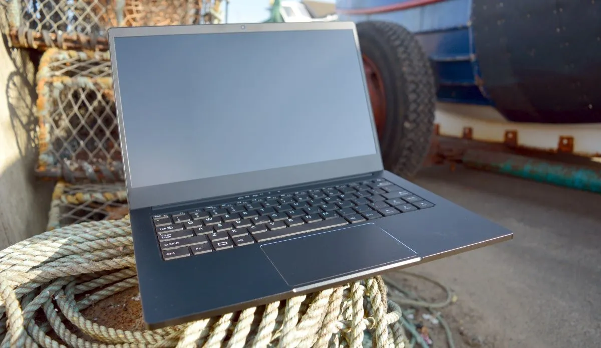 Laptop Purism Librem màu xám bạc đặt trên thùng xe bán tải gần trang trại, thể hiện tính di động