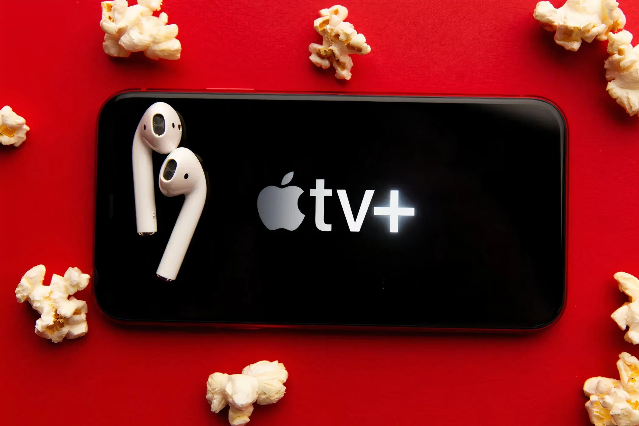 Màn hình điện thoại hiển thị logo Apple TV+ với bỏng ngô và tai nghe, thể hiện trải nghiệm xem phim di động.