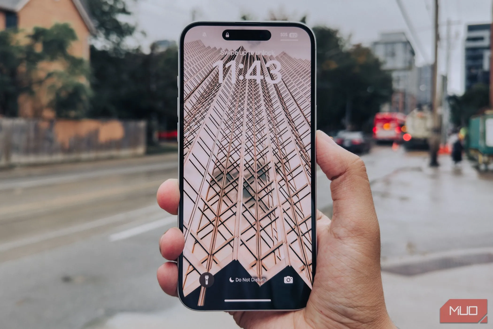Màn hình iPhone 16 Plus trong tay với nền thành phố