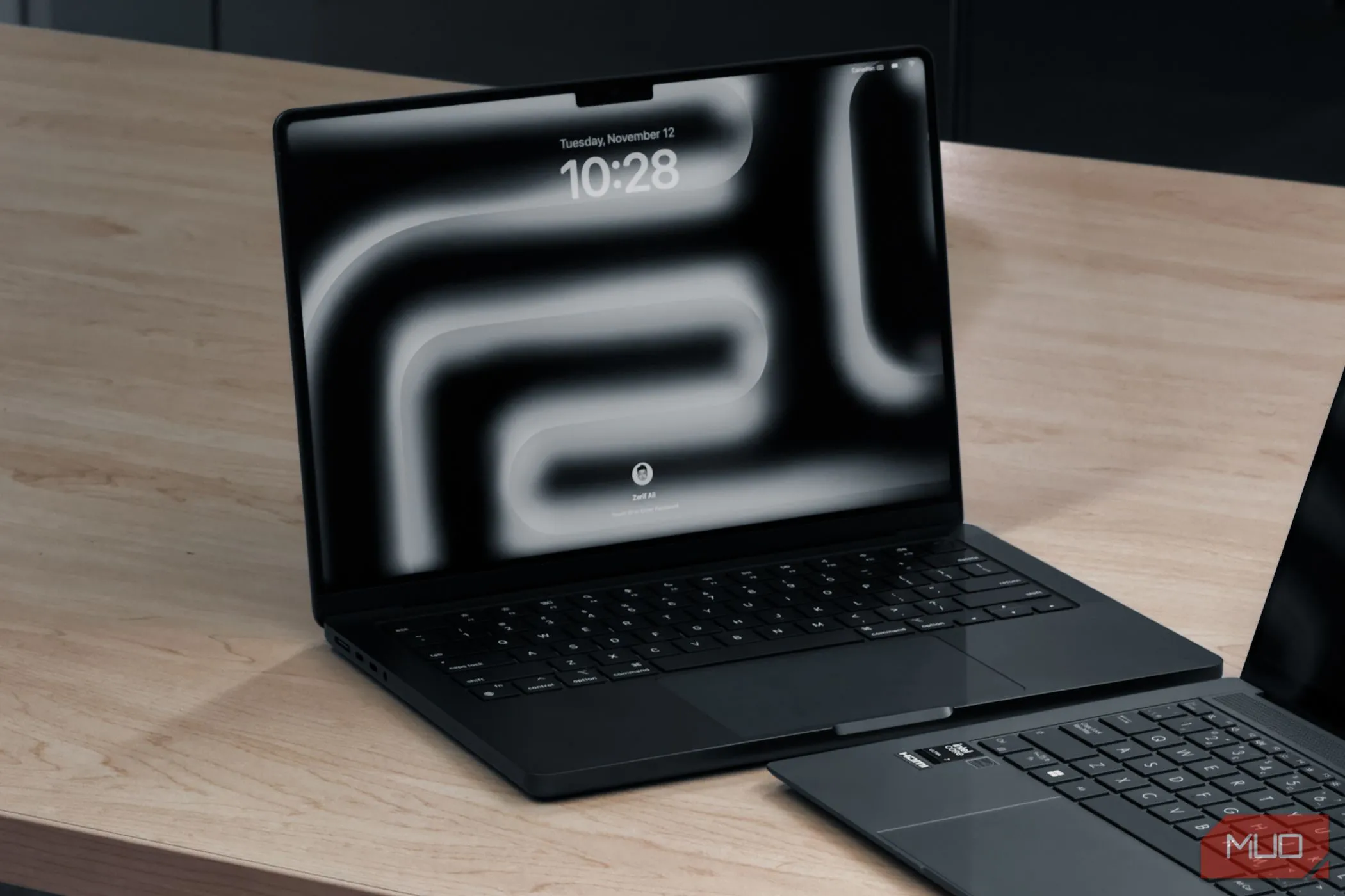 Máy tính xách tay MacBook Pro M4 và một laptop khác đặt trên bàn gỗ, thể hiện sự sang trọng và hiệu quả của macOS