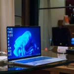 Máy tính xách tay Windows đặt trên bàn kính với các biểu tượng ứng dụng trên màn hình nền, minh họa cho việc sử dụng laptop hàng ngày.