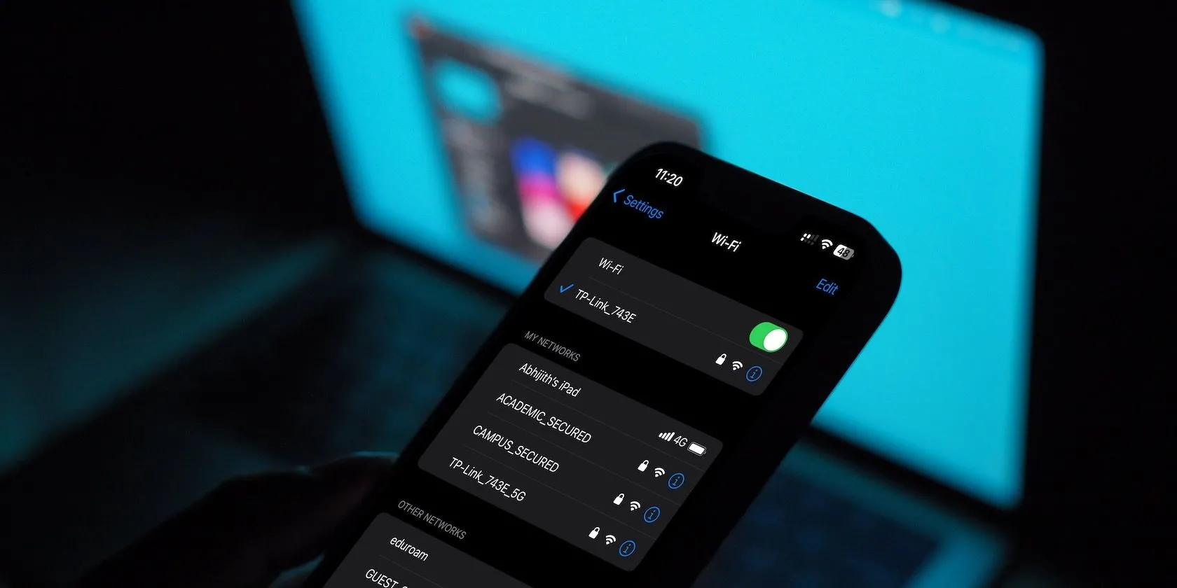 Menu cài đặt Wi-Fi trên iPhone với MacBook ở nền