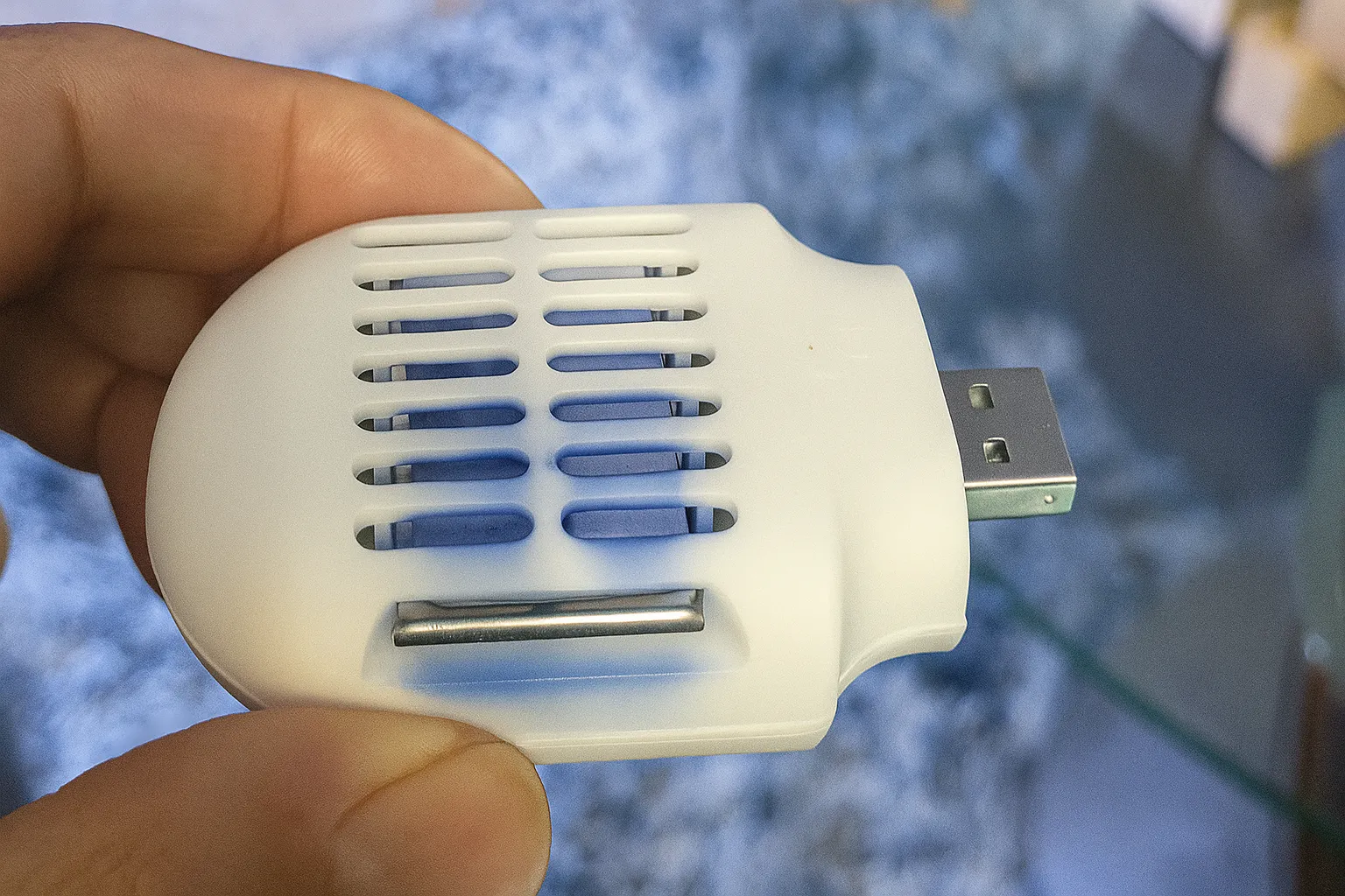 Một bàn tay cầm thiết bị đuổi muỗi USB màu trắng nhỏ gọn