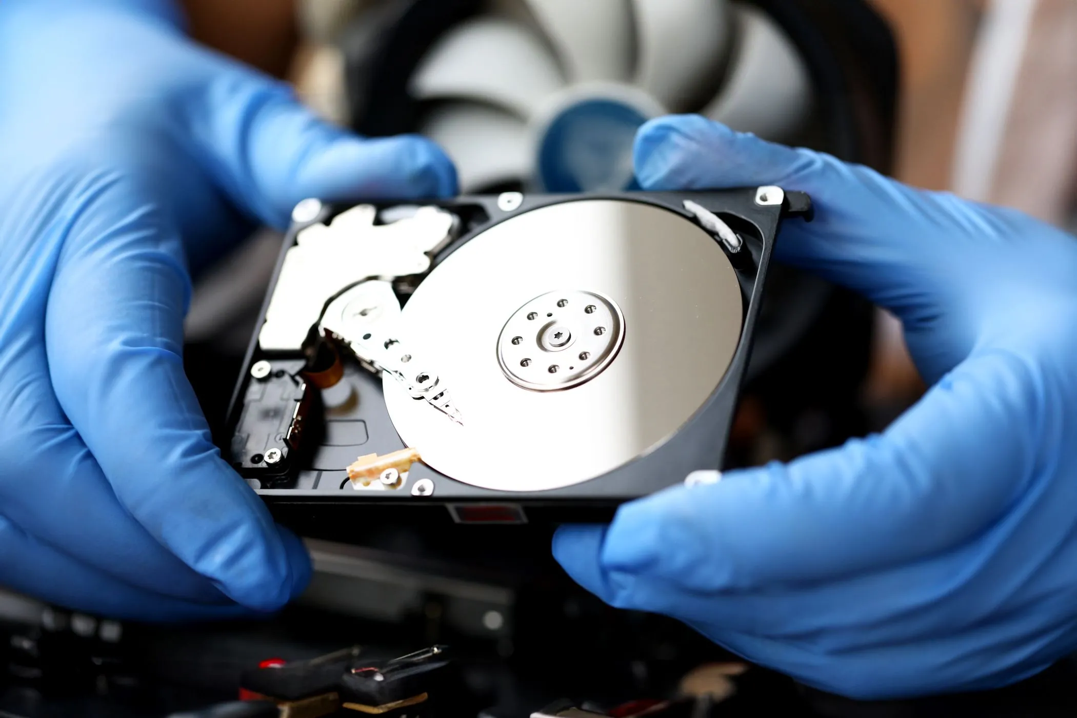 Một người đang cầm ổ cứng HDD với đĩa từ bên trong, biểu thị dung lượng lưu trữ hạn chế của Chromebook.