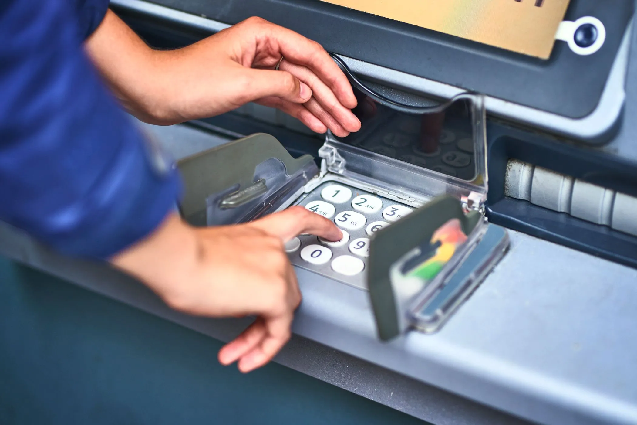 Một người đang nhập mã PIN trên thiết bị ATM.