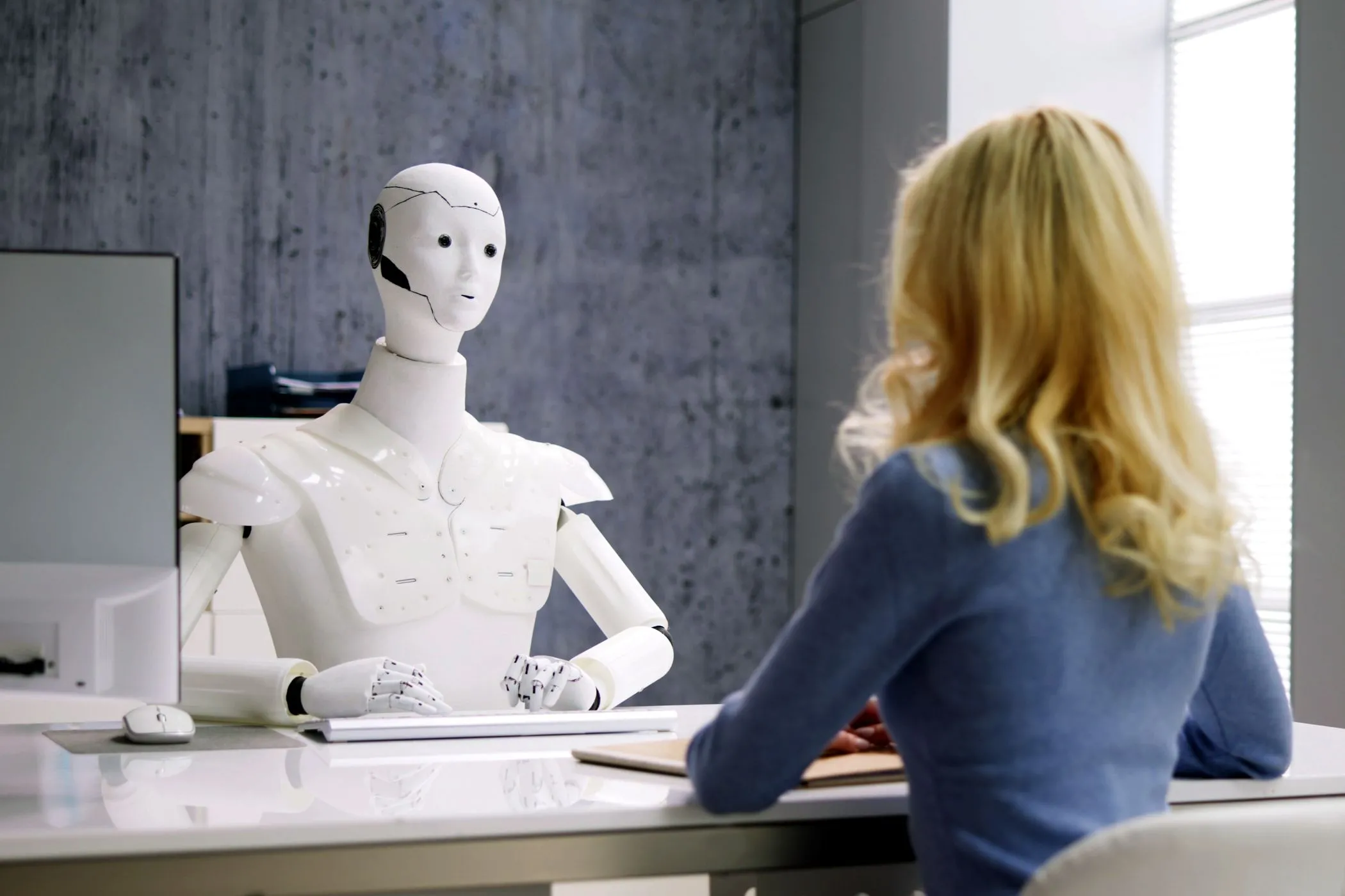 Một phụ nữ phỏng vấn với robot AI, biểu tượng của sự tương tác giữa con người và AI Agent trong công việc.