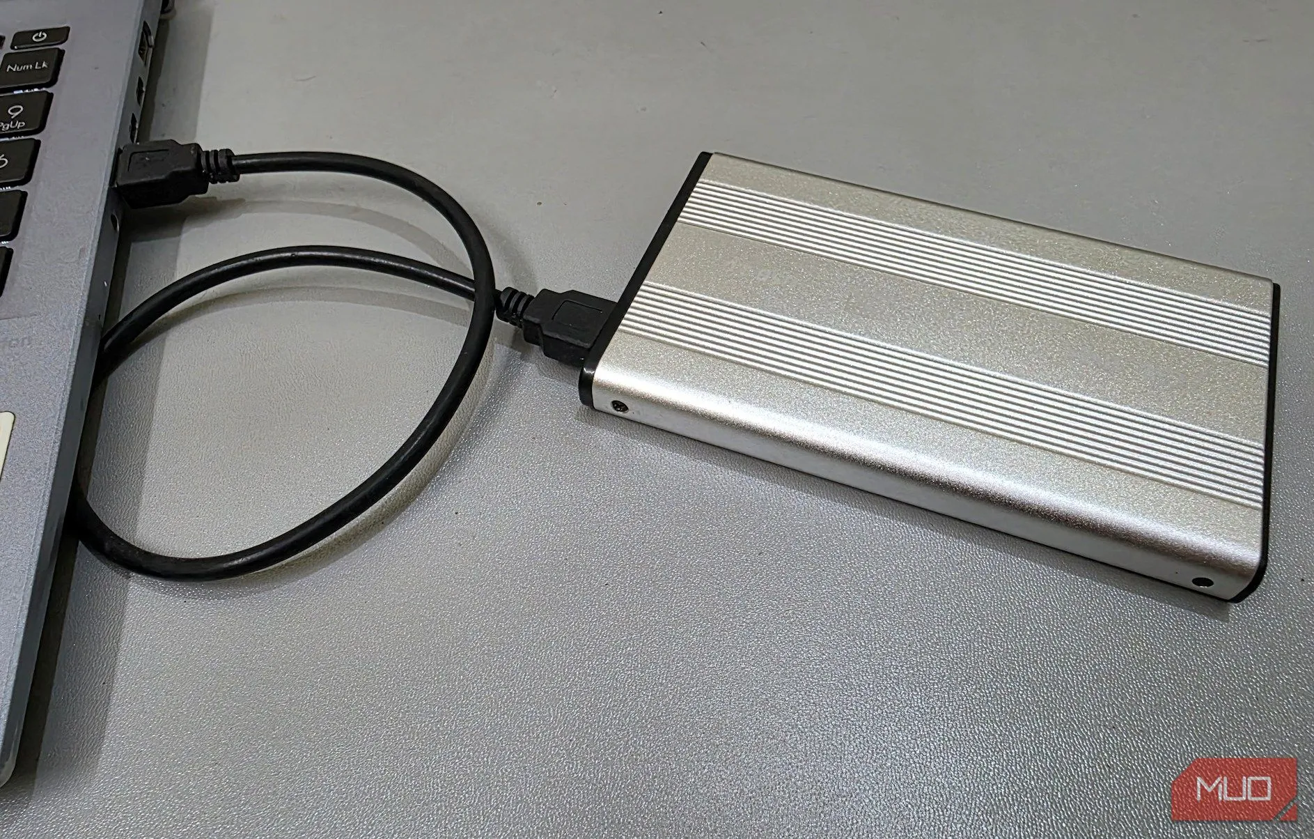 Một vỏ bọc ổ cứng ngoài (external hard drive enclosure) được kết nối với máy tính xách tay, thể hiện việc sử dụng ổ cứng cũ làm kho dữ liệu bảo mật.