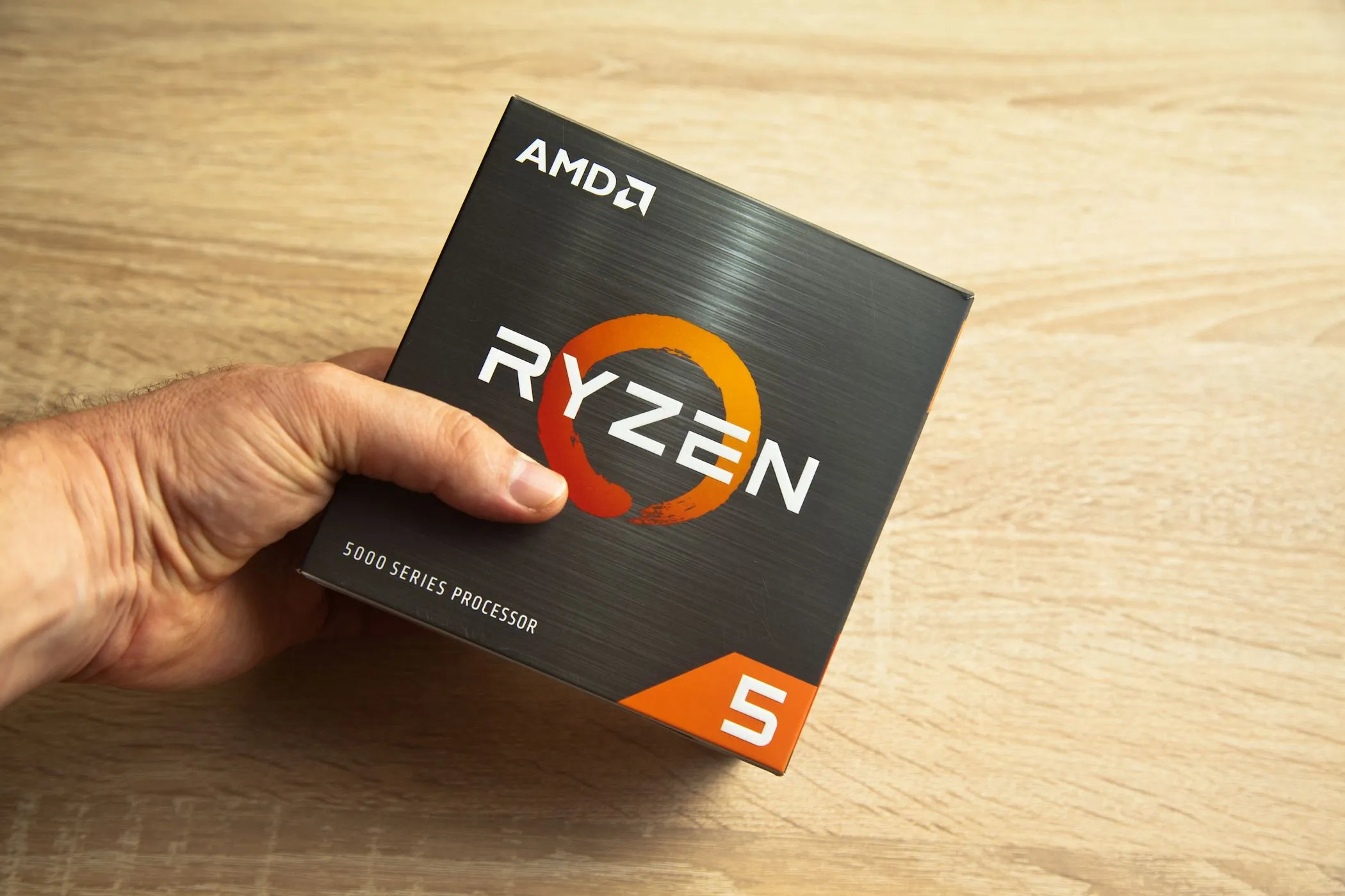 Người đàn ông cầm hộp vi xử lý AMD Ryzen 5, biểu tượng cho sức mạnh chip laptop