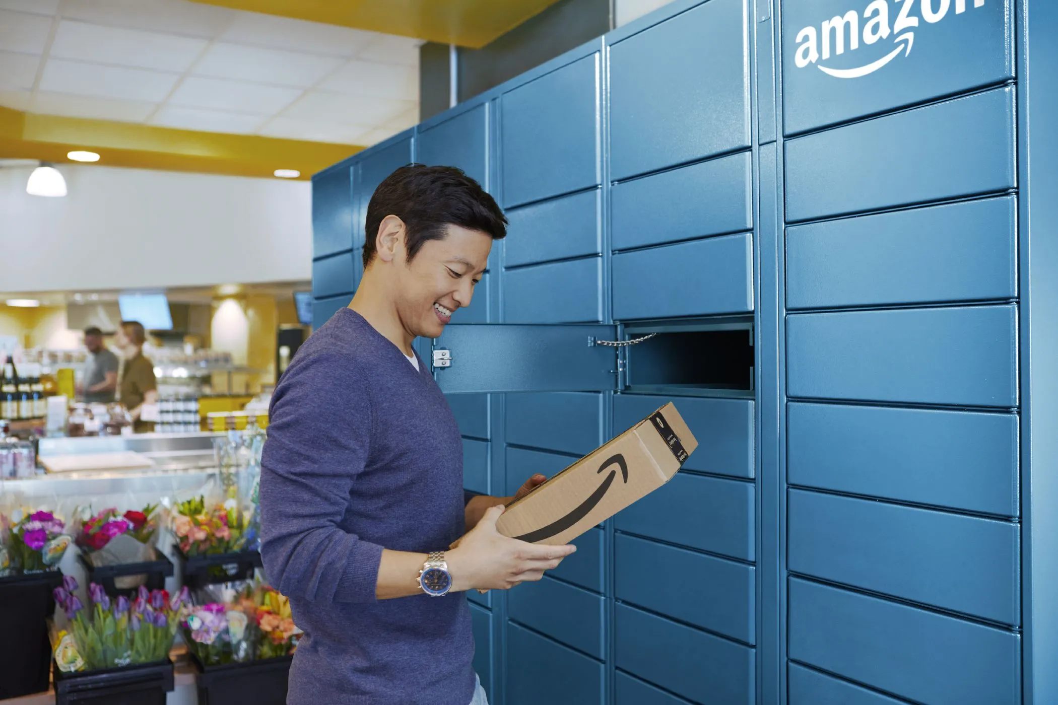 Người đàn ông đang nhận gói hàng từ Tủ khóa Amazon Locker, thể hiện phương pháp giao hàng thay thế giúp bảo mật địa chỉ nhà riêng và duy trì quyền riêng tư khi mua sắm online.