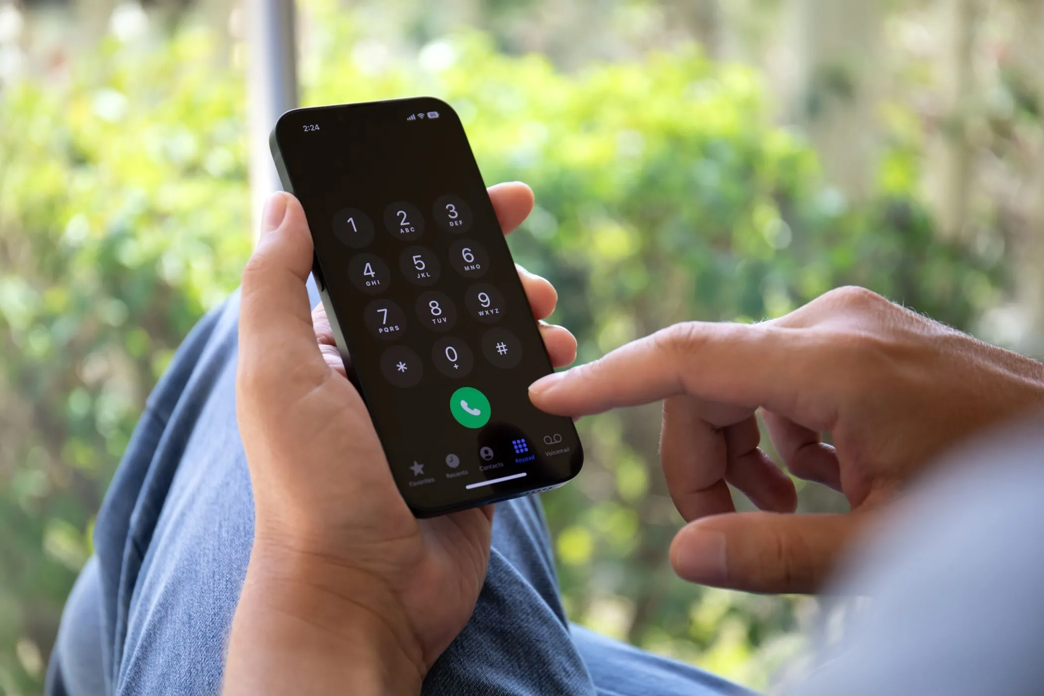 Người đàn ông đang nhập số điện thoại trên iPhone, thể hiện sự phụ thuộc của xác thực 2 yếu tố SMS vào tín hiệu di động