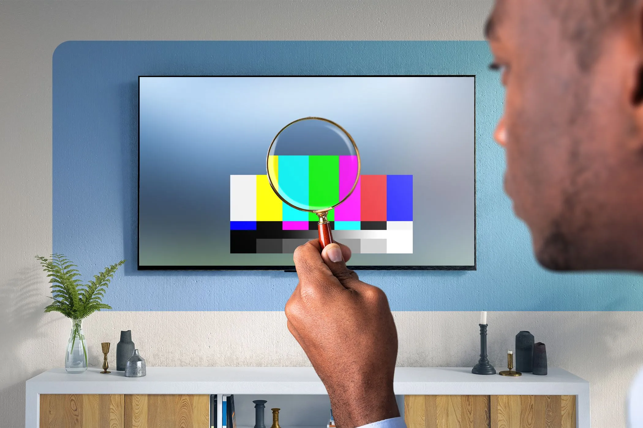 Người đàn ông với kính lúp đang kiểm tra chi tiết trên màn hình TV, thể hiện sự quan tâm đến chất lượng hình ảnh và dải màu rộng của HDR.