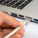 Người dùng cắm cáp Ethernet vào cổng mạng LAN trên laptop Windows
