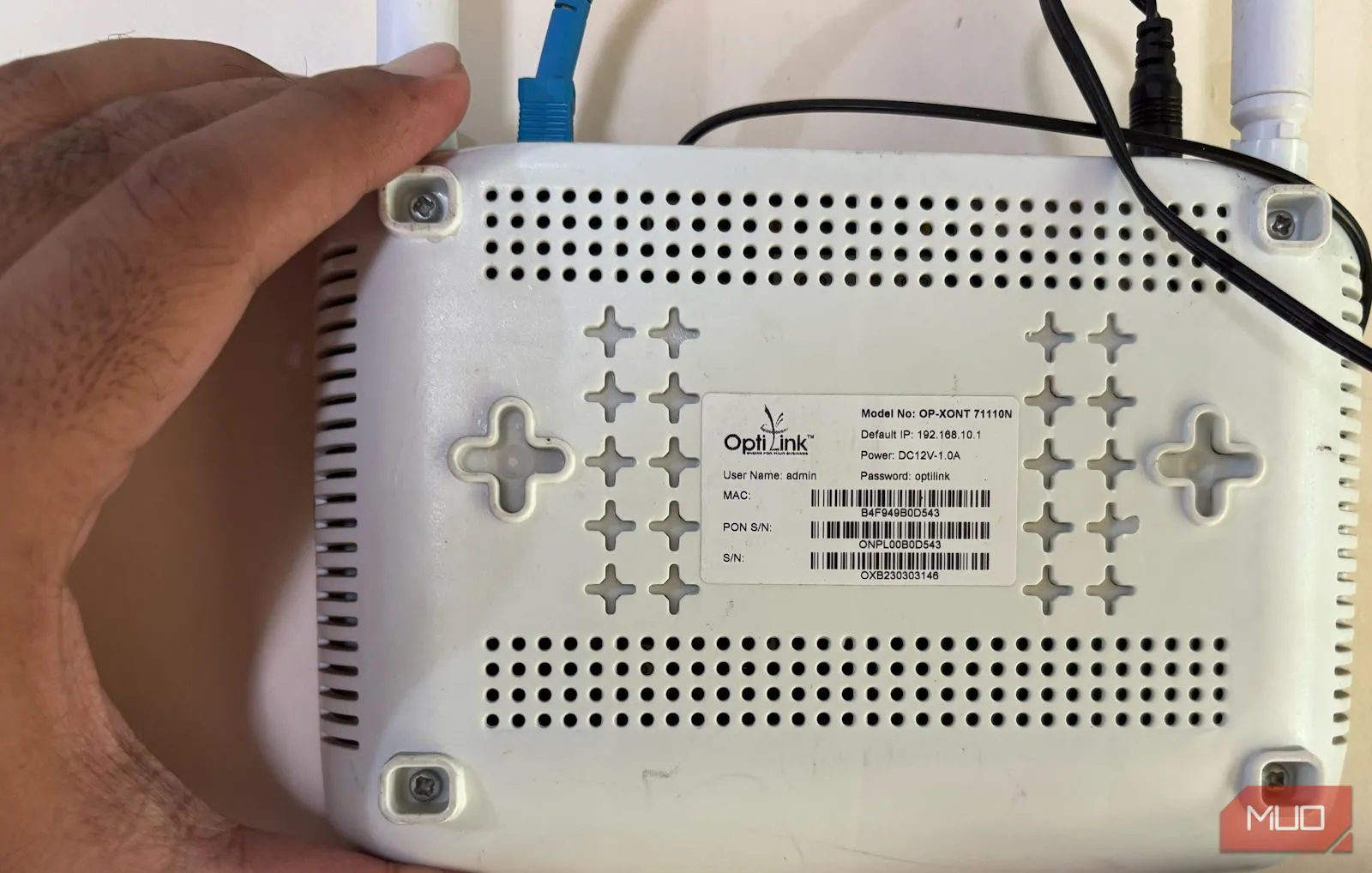 Người dùng đang cầm bộ định tuyến Wi-Fi để kiểm tra thông tin đăng nhập mặc định phía sau thiết bị.