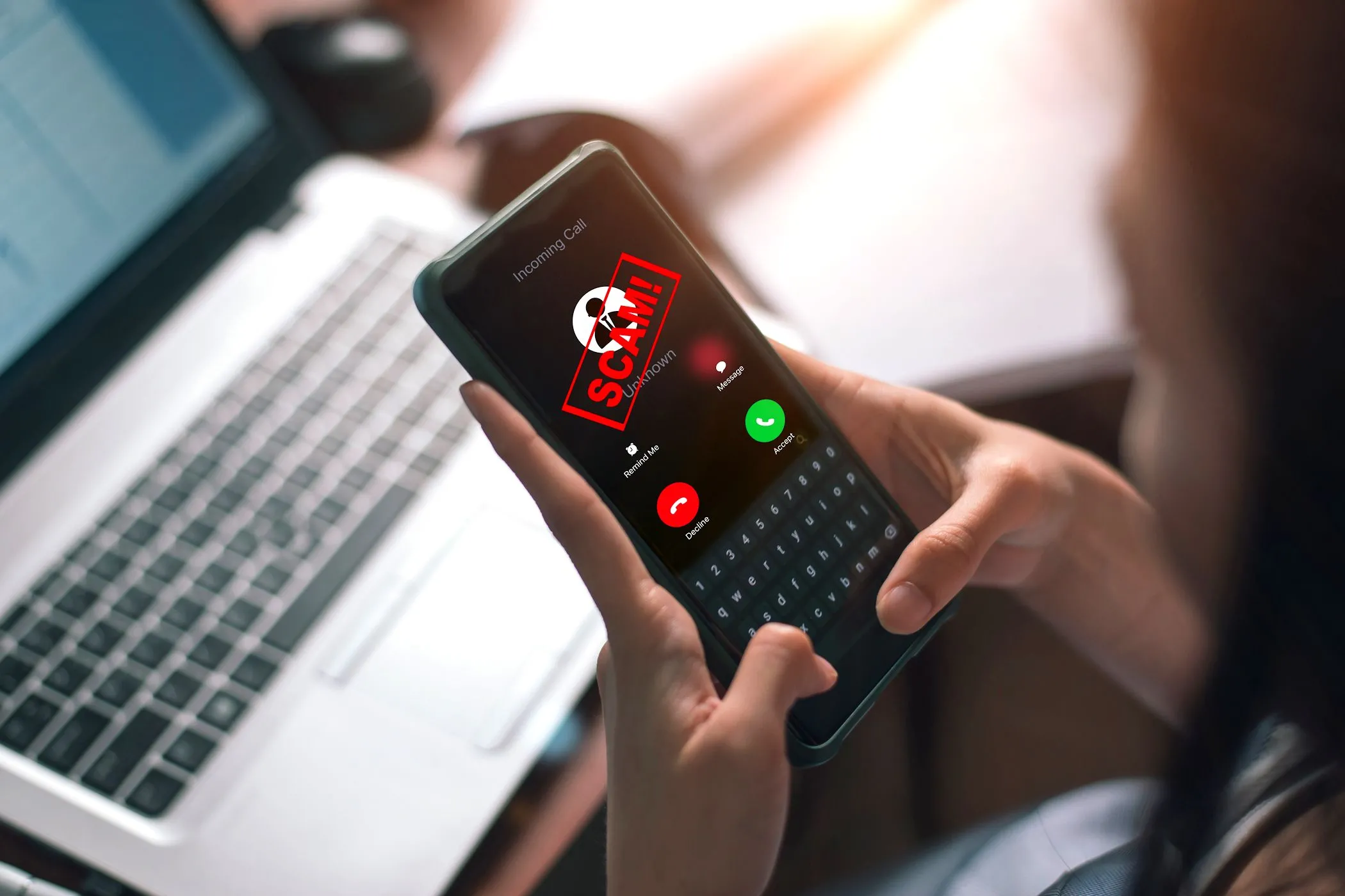 Người phụ nữ đang trả lời cuộc gọi điện thoại với cảnh báo lừa đảo trên màn hình