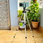 Người phụ nữ sử dụng chân máy ảnh tripod để chụp ảnh phong cảnh đêm thành phố bằng điện thoại, giúp ảnh sắc nét và ổn định