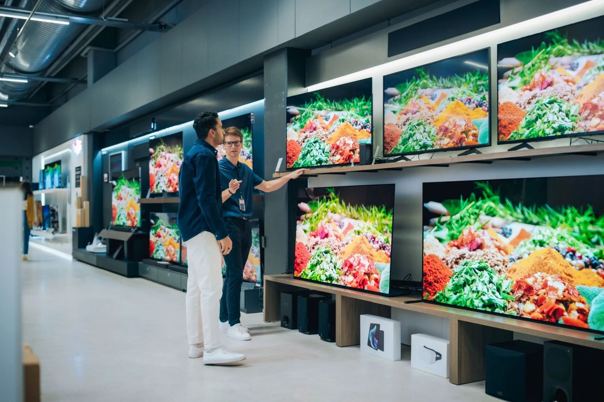 Nhân viên cửa hàng giới thiệu TV cho khách hàng