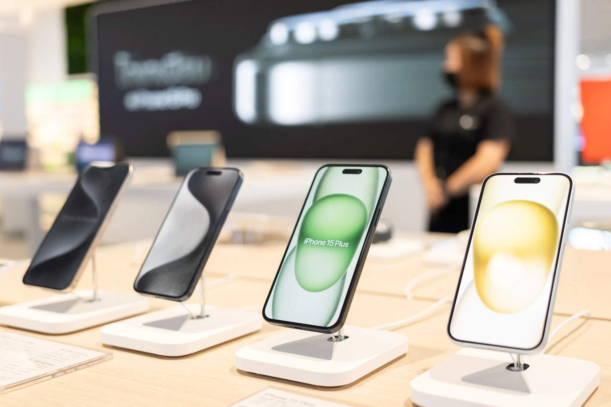 Nhiều mẫu iPhone 15 mới tinh xếp cạnh nhau trên kệ trưng bày tại một cửa hàng Apple Store