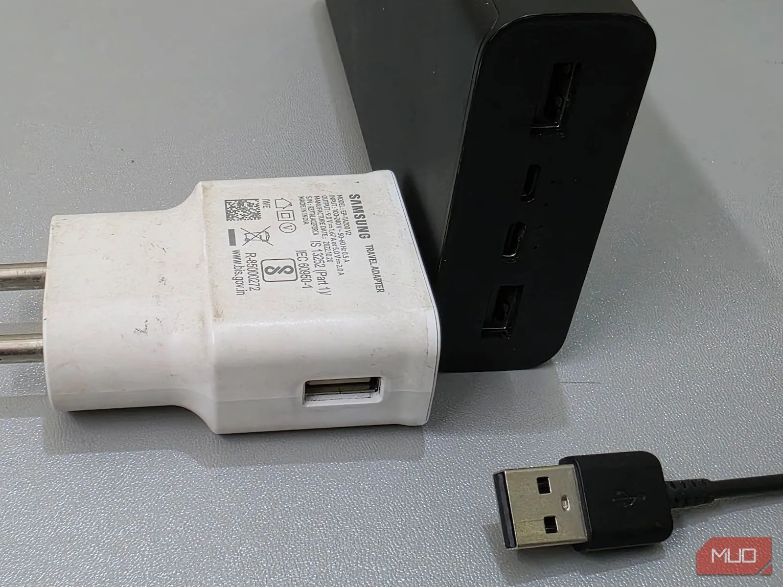 Pin sạc dự phòng, cáp sạc USB-C và củ sạc Samsung USB-A trên bàn, thể hiện sự đa dạng phụ kiện sạc