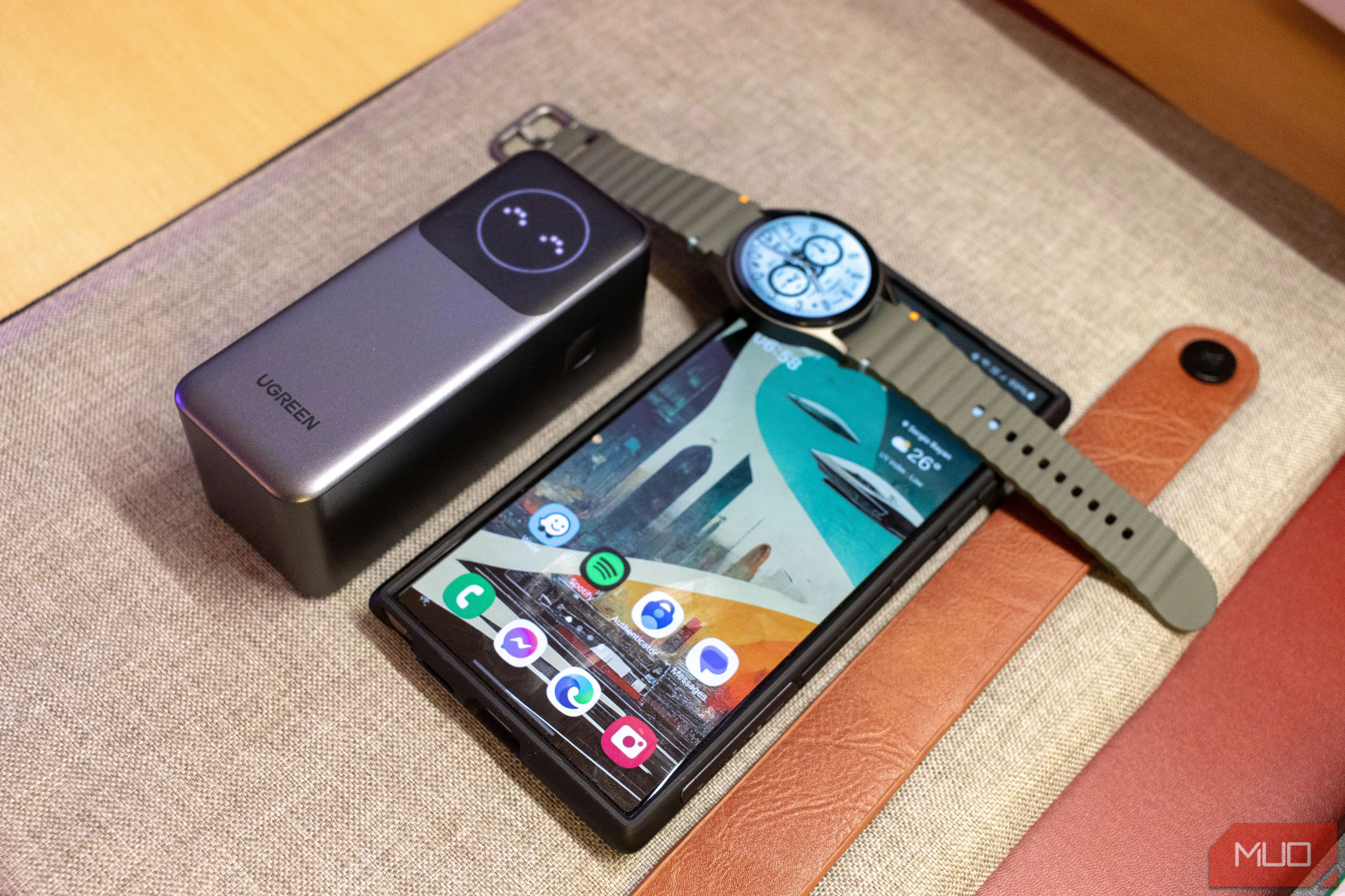 Pin sạc Ugreen Nexode 12000mAh bên cạnh Samsung S24 Ultra và đồng hồ thông minh Galaxy Watch7, minh họa khả năng sạc đa thiết bị