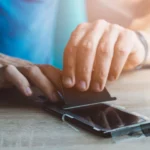 Tấm dán màn hình kháng khuẩn đang được dán lên điện thoại iPhone.