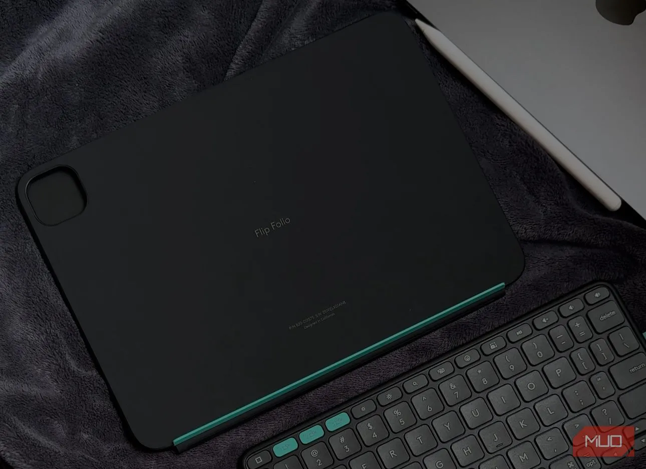 Vỏ bảo vệ Logitech Flip Folio và iPad đặt trên chăn, hiển thị các phím tắt iPadOS